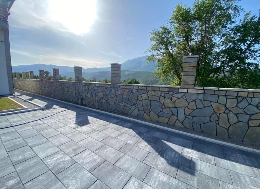 Große Pflasterfläche mit Natursteinmauer